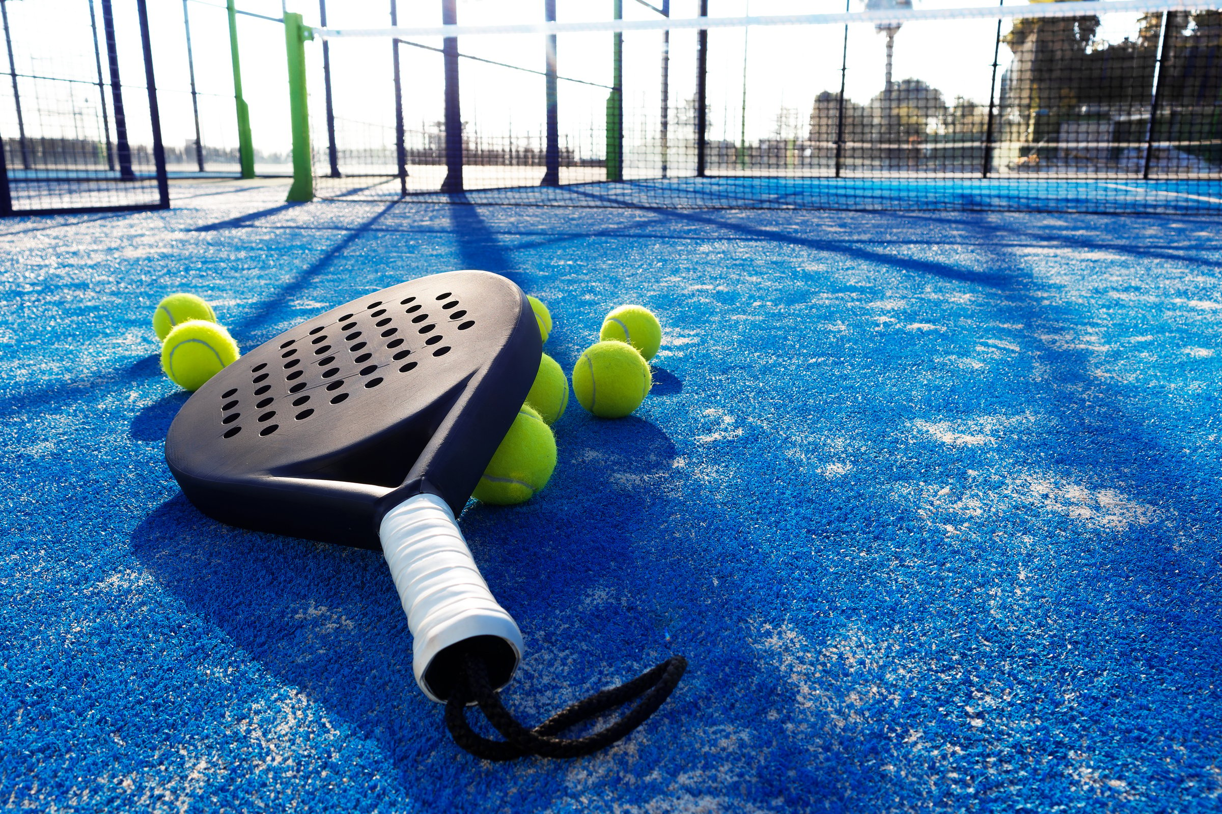 paddle tennis racket and balls on the blue paddle court